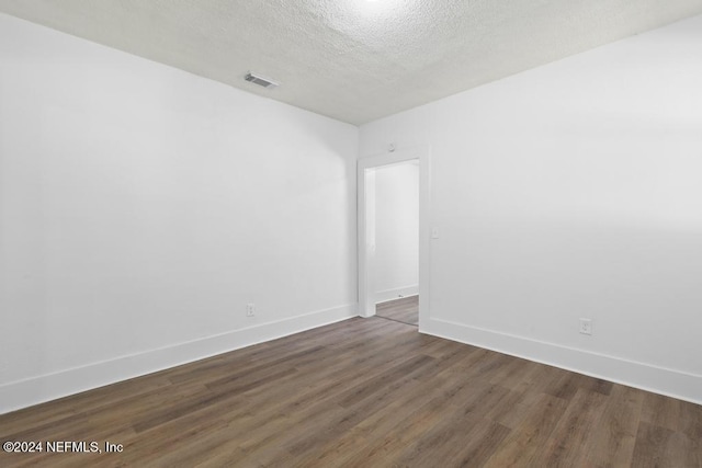 spare room featuring dark hardwood / wood-style flooring and a textured ceiling