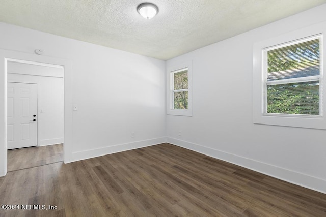 empty room featuring dark hardwood / wood-style floors, a textured ceiling, and a wealth of natural light