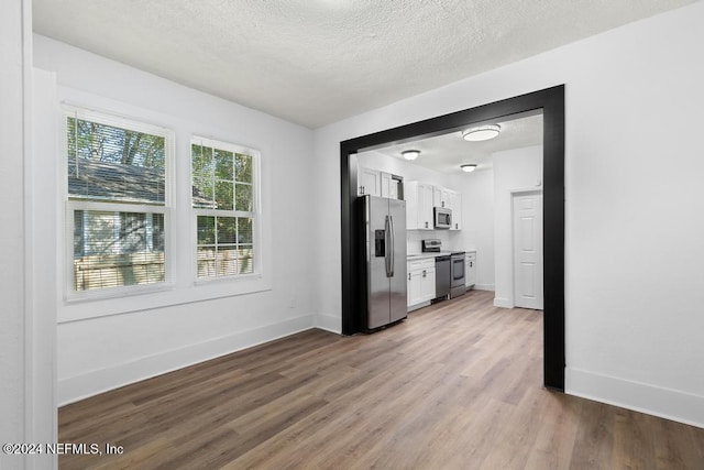 kitchen featuring white cabinetry, light wood-type flooring, a textured ceiling, and appliances with stainless steel finishes