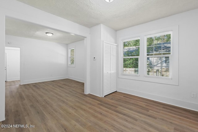 spare room featuring a textured ceiling and dark hardwood / wood-style floors