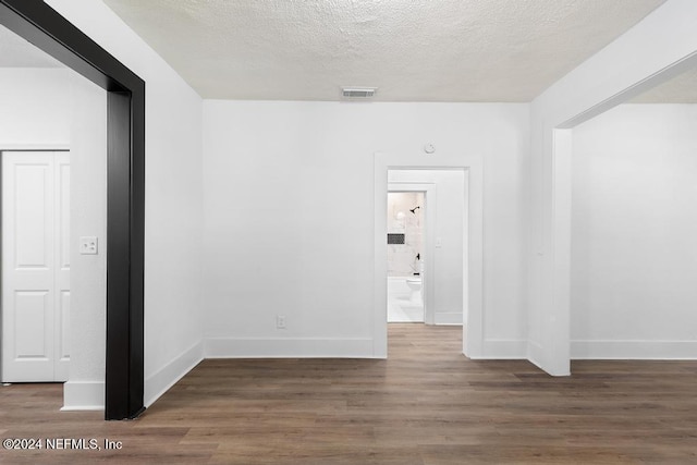 spare room featuring a textured ceiling and dark wood-type flooring