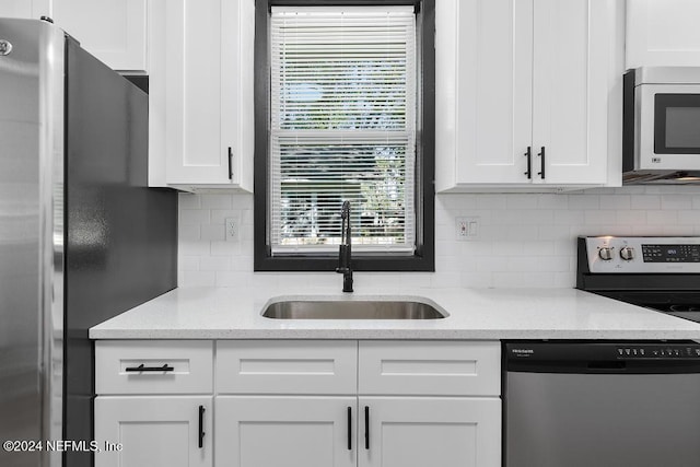 kitchen with white cabinets, backsplash, sink, and appliances with stainless steel finishes