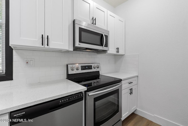 kitchen with white cabinets, appliances with stainless steel finishes, backsplash, and dark hardwood / wood-style floors