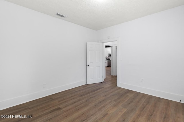 spare room featuring a textured ceiling and dark hardwood / wood-style flooring