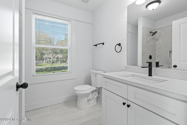 bathroom featuring tiled shower, vanity, and toilet