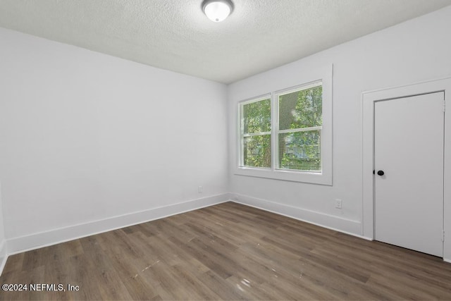 empty room featuring dark hardwood / wood-style flooring and a textured ceiling