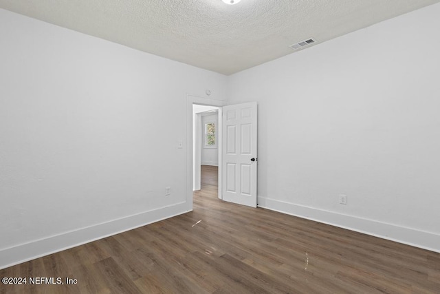 unfurnished room featuring a textured ceiling and dark hardwood / wood-style flooring