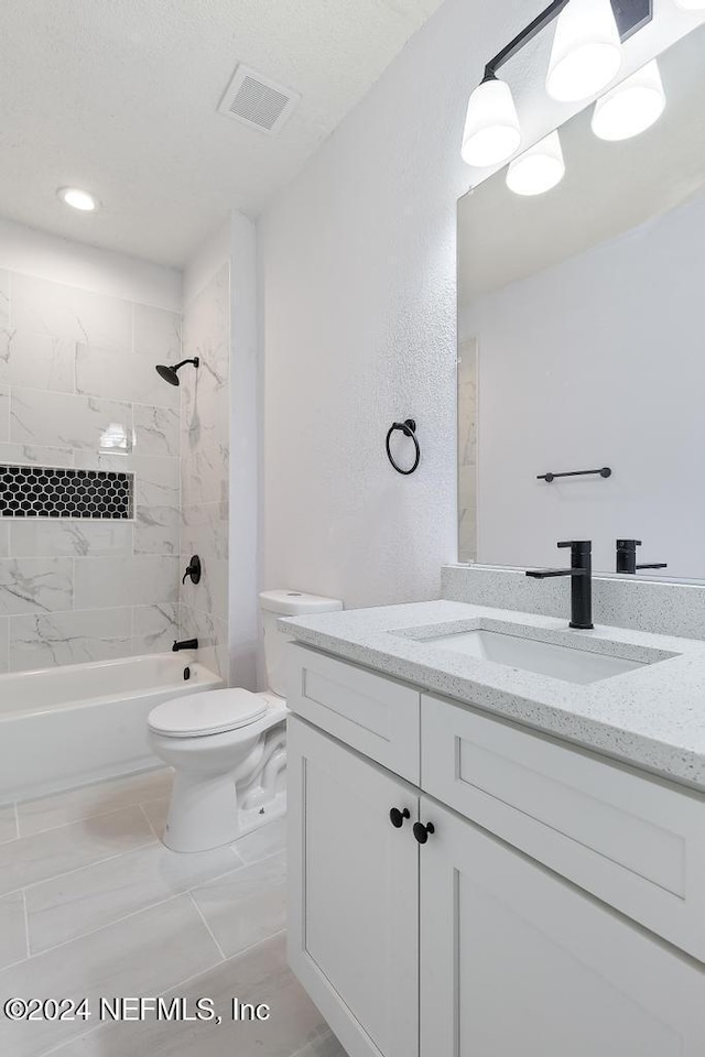 full bathroom featuring tile patterned floors, vanity, tiled shower / bath combo, and toilet