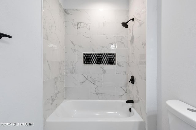 bathroom with tiled shower / bath combo and toilet