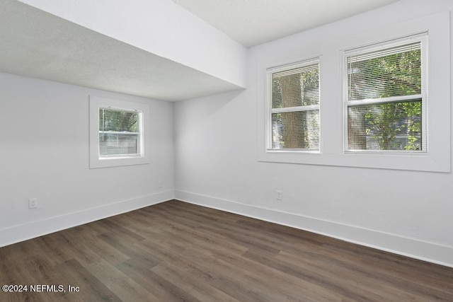 spare room featuring dark wood-type flooring and a healthy amount of sunlight