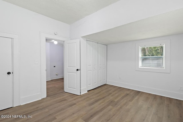 unfurnished bedroom with a textured ceiling and light hardwood / wood-style flooring