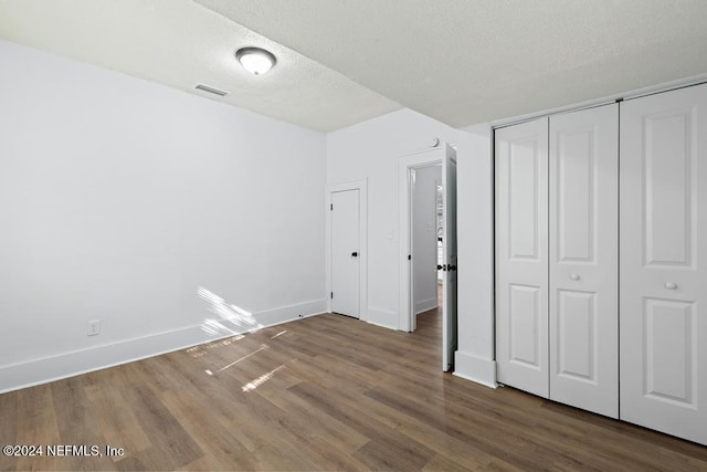 unfurnished bedroom featuring a textured ceiling, hardwood / wood-style flooring, and a closet