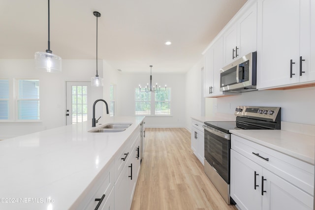 kitchen featuring decorative light fixtures, white cabinetry, sink, and appliances with stainless steel finishes