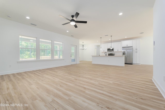 unfurnished living room with light hardwood / wood-style flooring and ceiling fan with notable chandelier