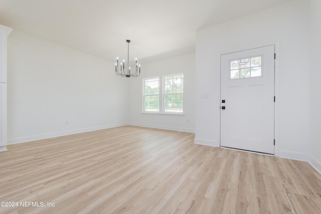 foyer with plenty of natural light, light wood-type flooring, and an inviting chandelier