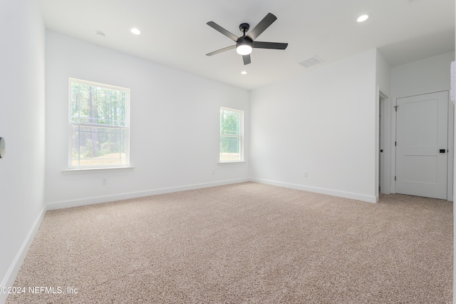 carpeted spare room featuring ceiling fan and a wealth of natural light