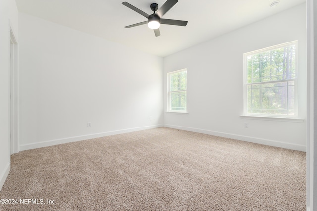 carpeted spare room featuring ceiling fan and a wealth of natural light