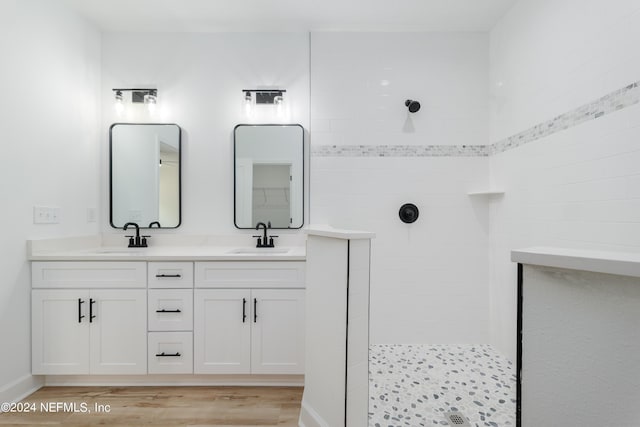 bathroom featuring hardwood / wood-style flooring, vanity, and a tile shower