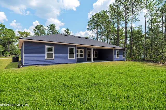 rear view of house featuring a lawn, cooling unit, and a patio