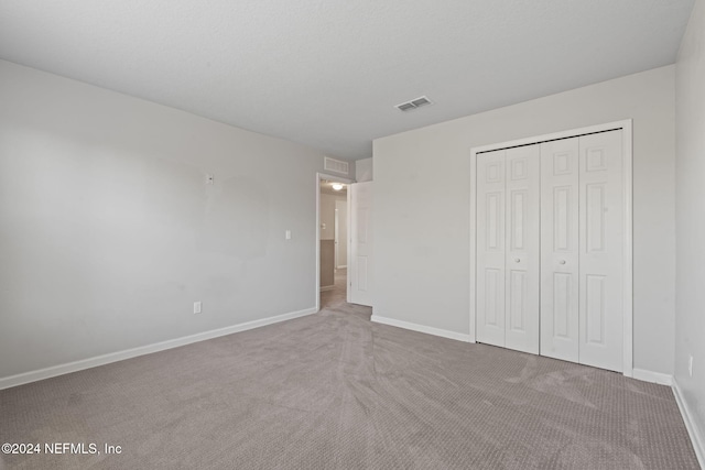 unfurnished bedroom with light carpet and a closet