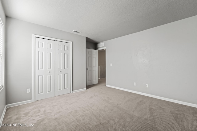 unfurnished bedroom with carpet, a textured ceiling, and a closet