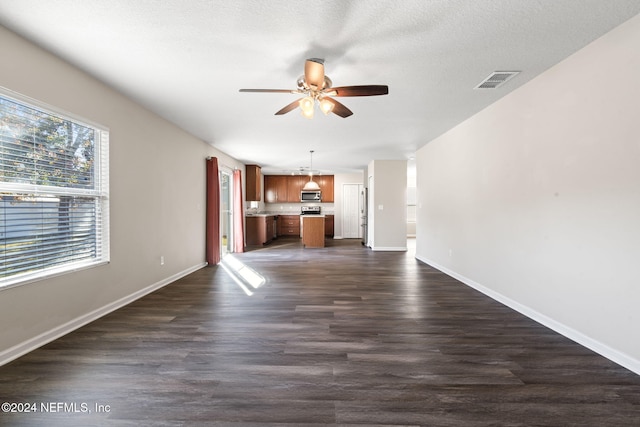 unfurnished living room featuring ceiling fan, dark hardwood / wood-style flooring, and a textured ceiling