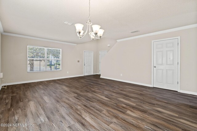 interior space with dark wood-type flooring, a notable chandelier, crown molding, lofted ceiling, and a textured ceiling