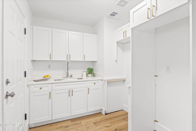 kitchen with white cabinetry, sink, and light hardwood / wood-style floors