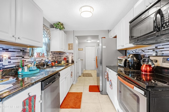 kitchen with white cabinets, appliances with stainless steel finishes, and dark stone counters