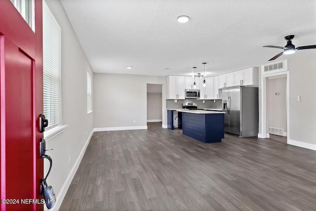 kitchen with hardwood / wood-style floors, pendant lighting, white cabinets, a kitchen island, and stainless steel appliances