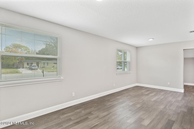 empty room with hardwood / wood-style floors and a textured ceiling