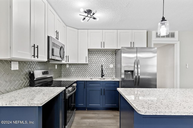 kitchen with white cabinetry, sink, hanging light fixtures, appliances with stainless steel finishes, and light wood-type flooring