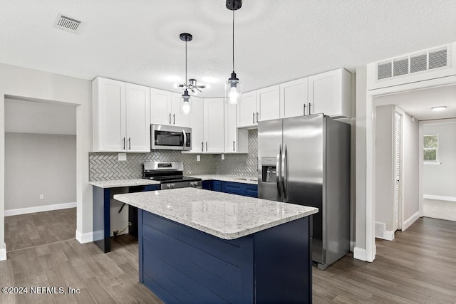 kitchen featuring pendant lighting, a kitchen island, white cabinetry, and appliances with stainless steel finishes