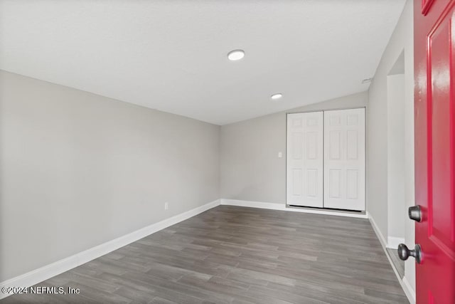 unfurnished bedroom featuring lofted ceiling, dark wood-type flooring, and a closet