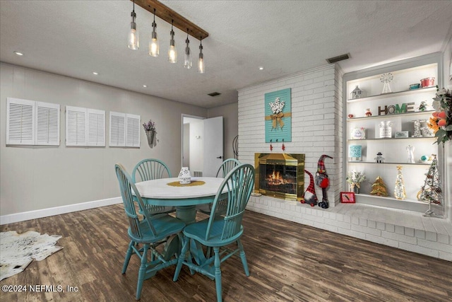 dining area with a brick fireplace, a textured ceiling, and dark wood-type flooring