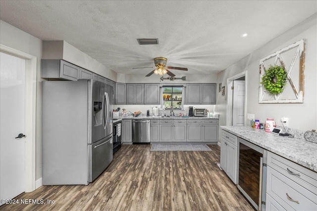 kitchen with gray cabinetry, wine cooler, a textured ceiling, and appliances with stainless steel finishes