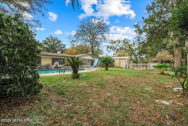 view of yard featuring a fenced in pool and a storage shed