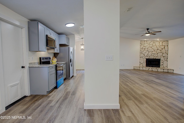 kitchen featuring light wood-style floors, a fireplace, baseboards, and stainless steel appliances