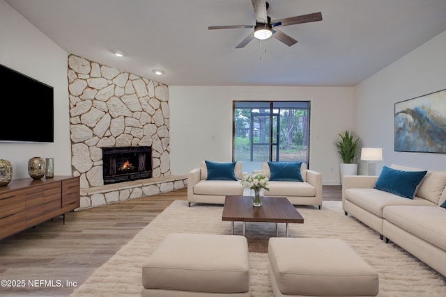 living room with lofted ceiling, light wood finished floors, ceiling fan, and a fireplace