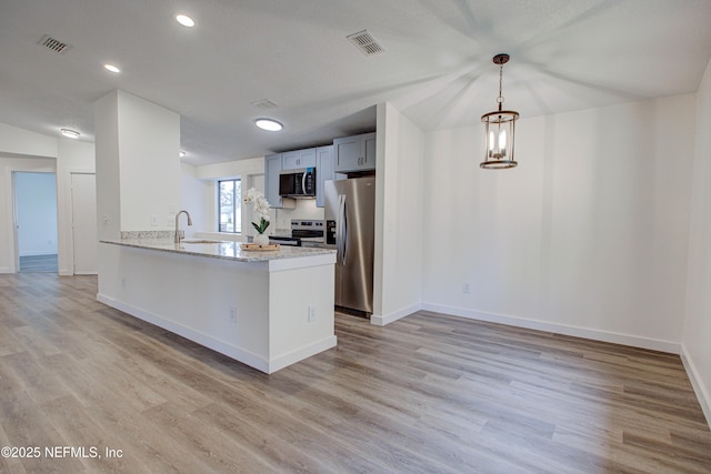 kitchen featuring stainless steel appliances, visible vents, a sink, and light wood finished floors