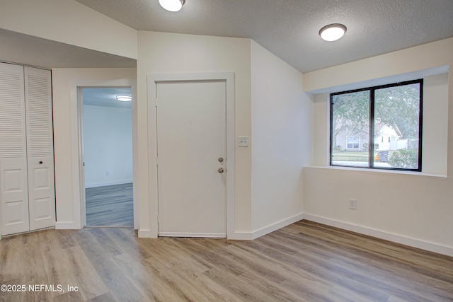 entrance foyer featuring light wood-type flooring, baseboards, and a textured ceiling