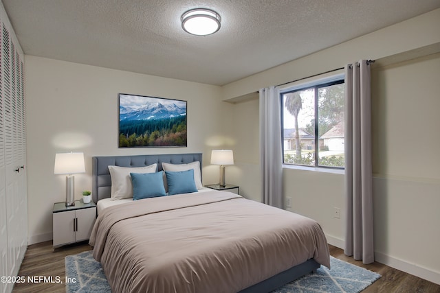 bedroom with a textured ceiling, baseboards, and wood finished floors