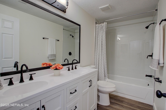 full bath featuring toilet, a textured ceiling, a sink, and wood finished floors