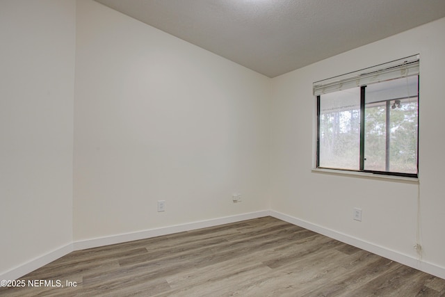 spare room featuring baseboards and wood finished floors