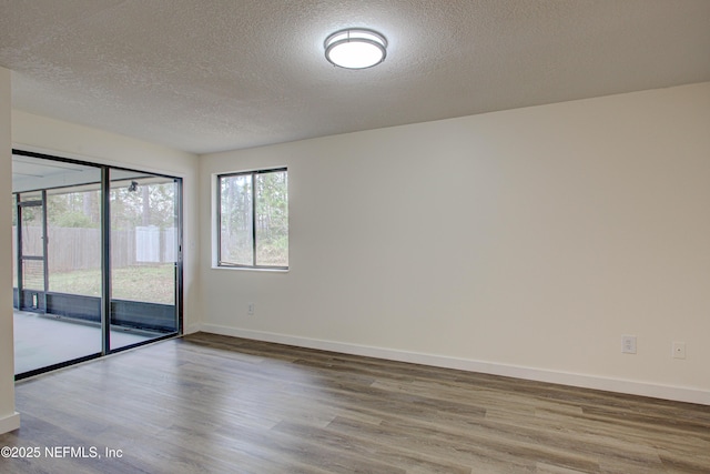 unfurnished room featuring a textured ceiling, baseboards, and wood finished floors