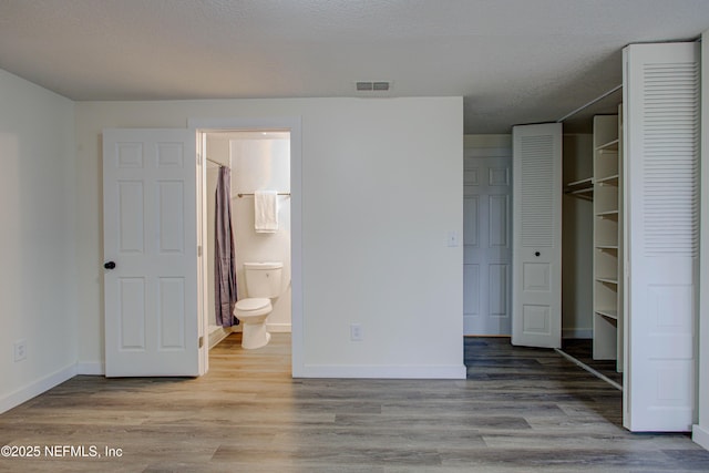 unfurnished bedroom featuring baseboards, visible vents, and wood finished floors