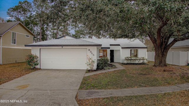 ranch-style home with a garage, driveway, and fence