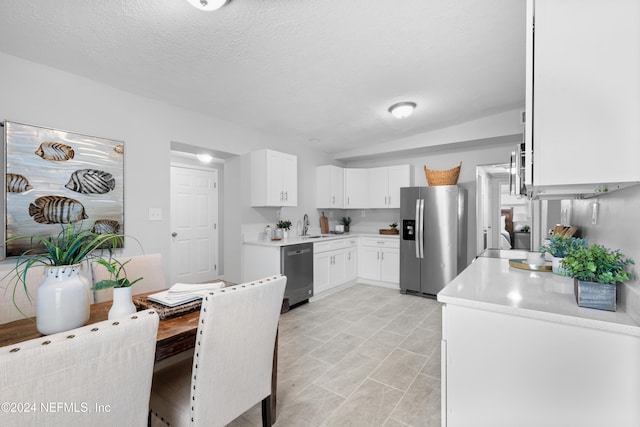 kitchen with appliances with stainless steel finishes, a textured ceiling, sink, light tile patterned floors, and white cabinetry