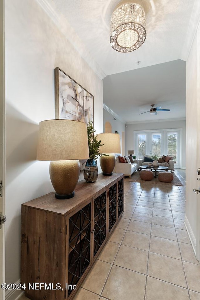 hallway with crown molding, light tile patterned floors, and a chandelier