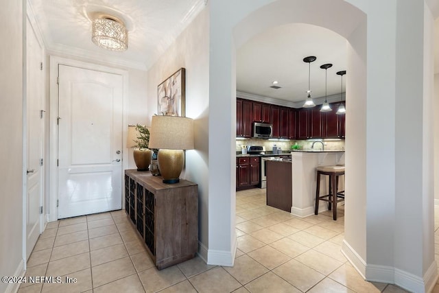 kitchen with decorative backsplash, a breakfast bar, stainless steel appliances, hanging light fixtures, and light tile patterned flooring